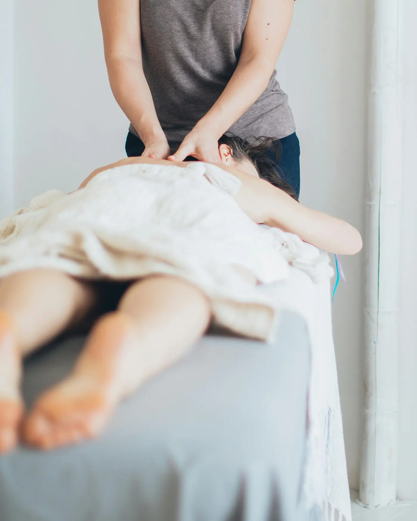 A therapist works on a client's neck and shoulders during a massage.