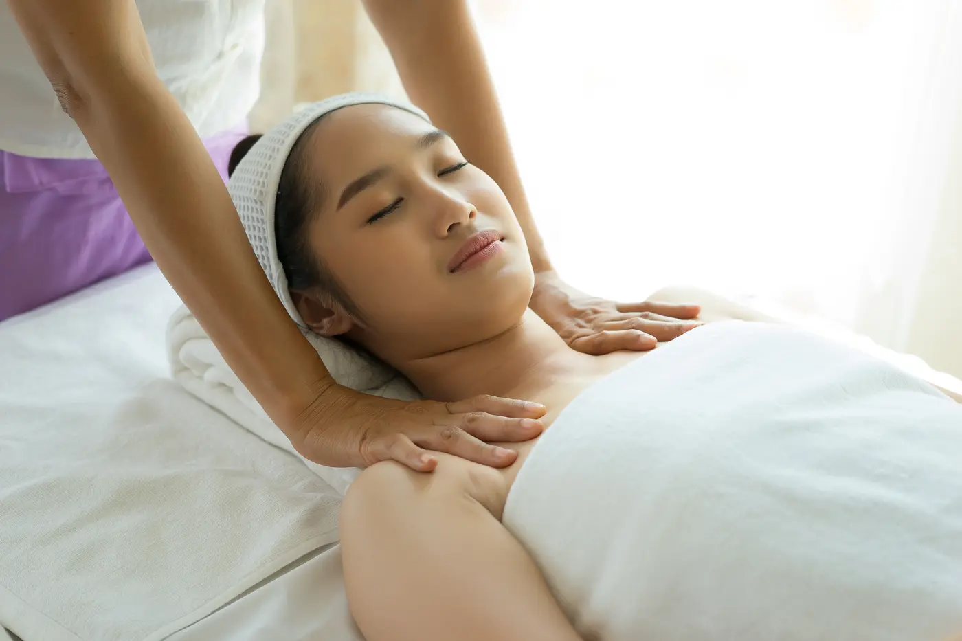 A woman lying on a covered massage table during a session.